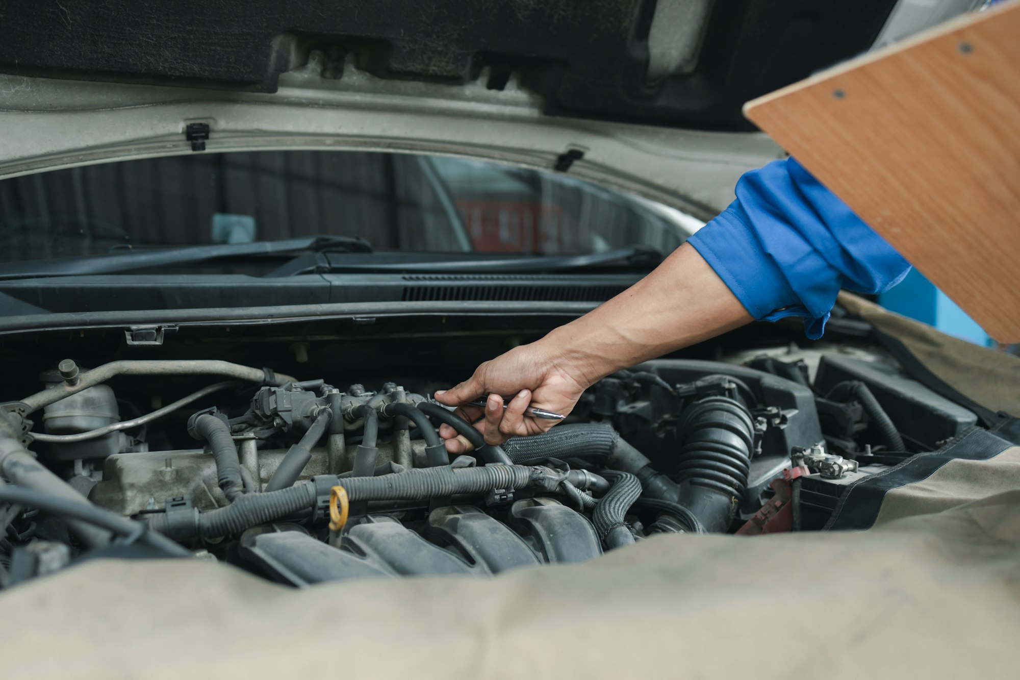 The mechanic is repairing the engine, A car repair worker is inspecting a car, A car mechanic is loo
