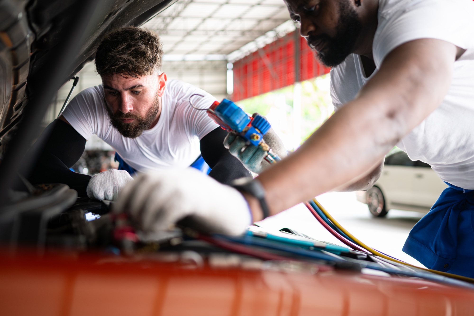 Car mechanic working in an auto repair shop, inspecting the operation of the car's air conditioner